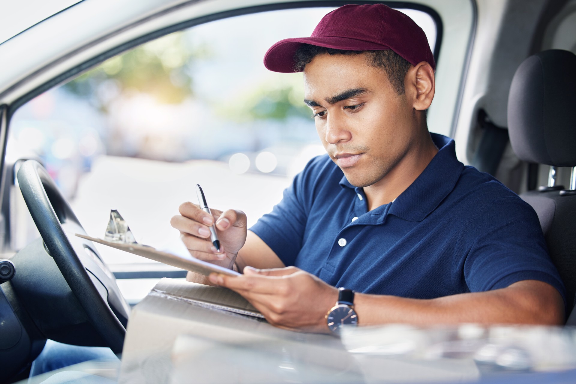 Shot of a young delivery man writing on a clipboard while sitting in a van